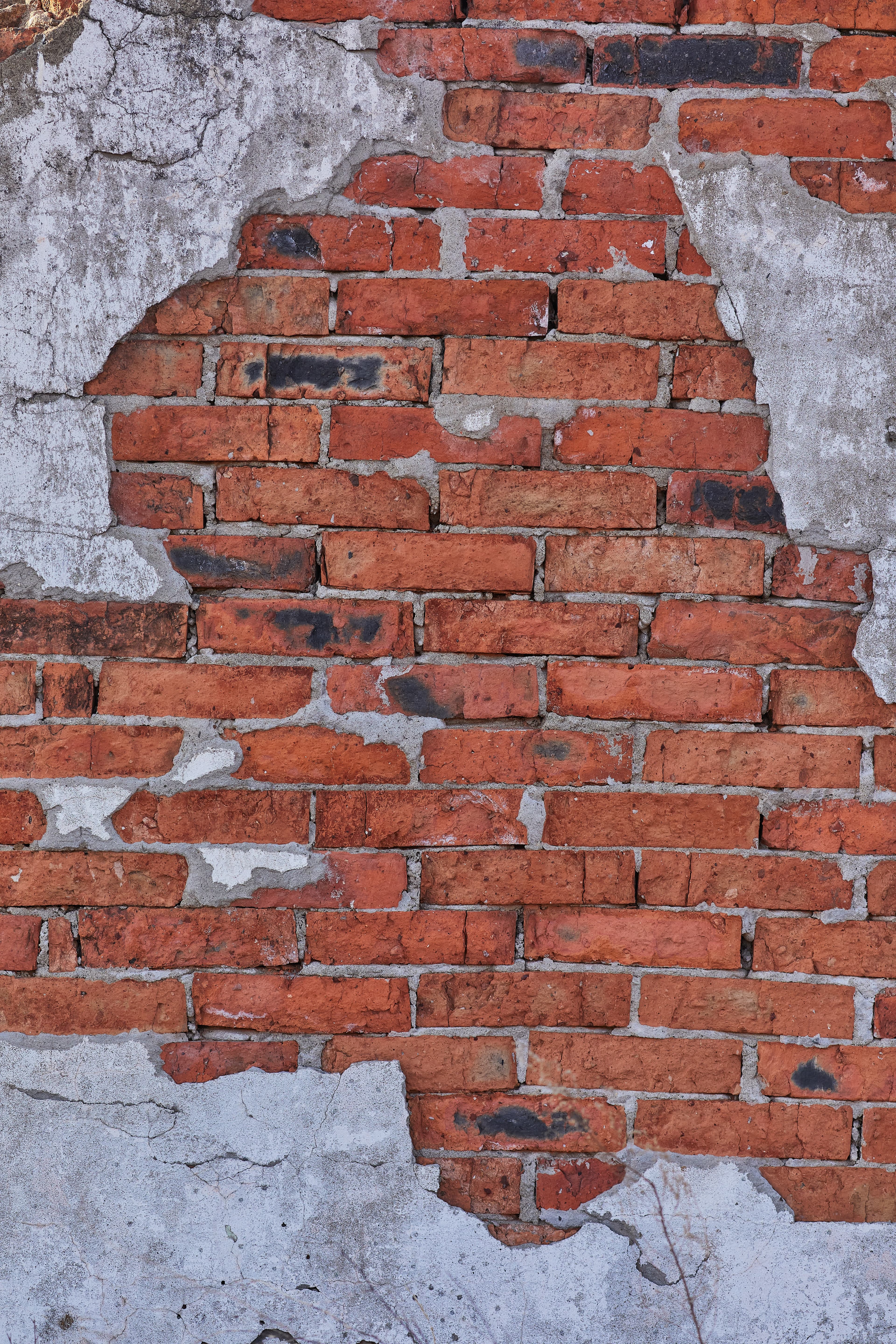 a red brick wall with some white plaster on it.