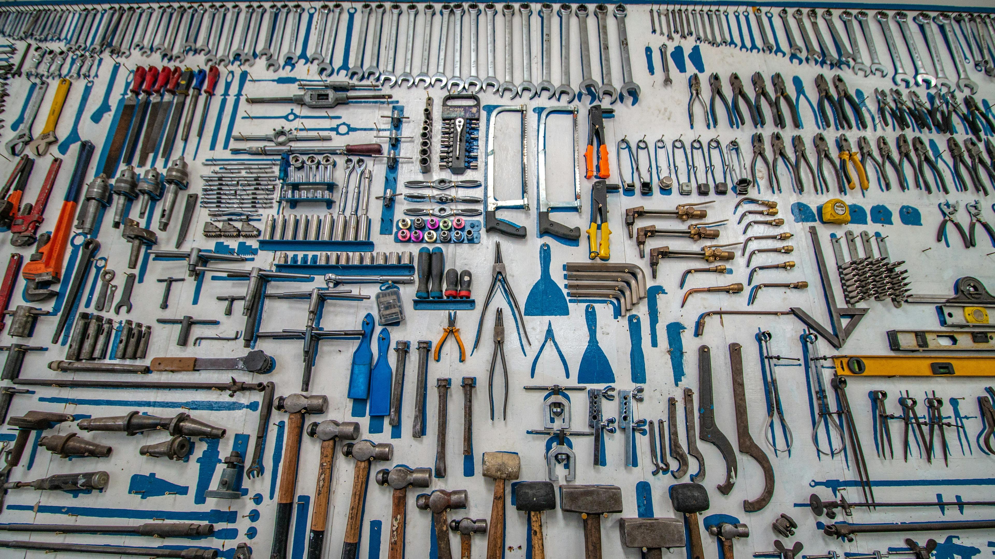 A variety of handheld tools hanging from a wall